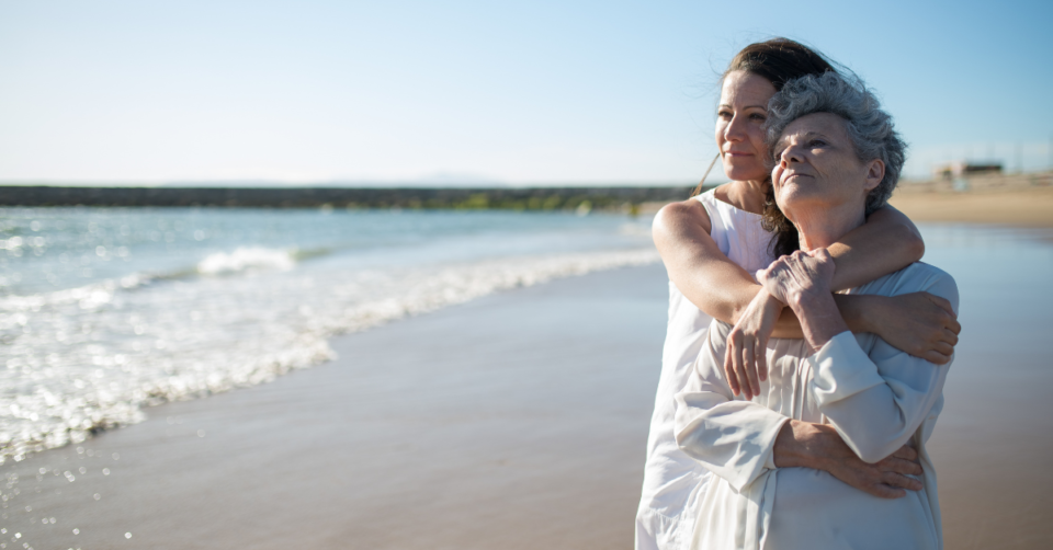 mum and daughter holding one another on a beach