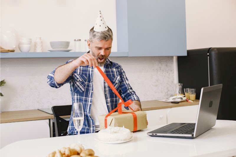 a man wearing a party hat opening a gift