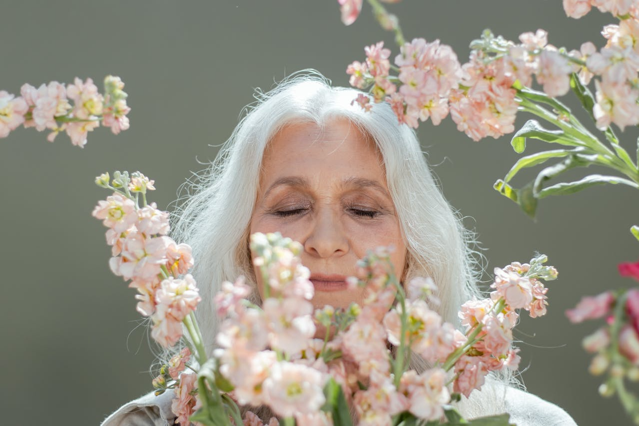 a lady with grey hair surrounded by pink flowers