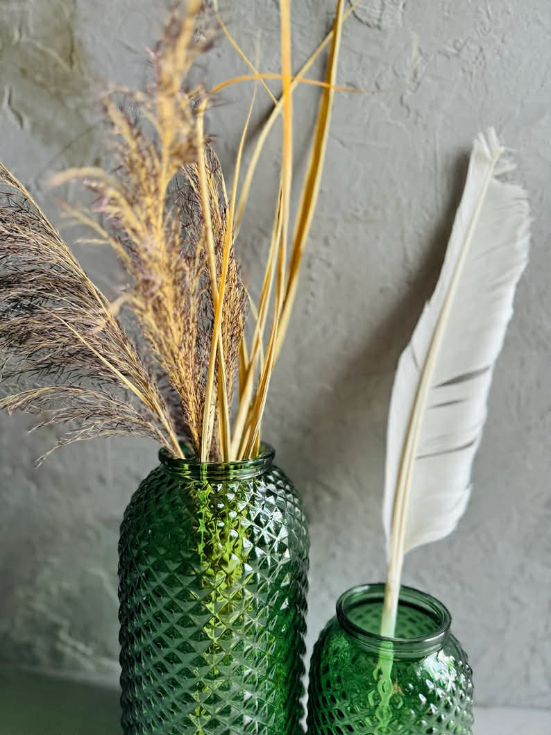 green vases with a feathe and dried flowers