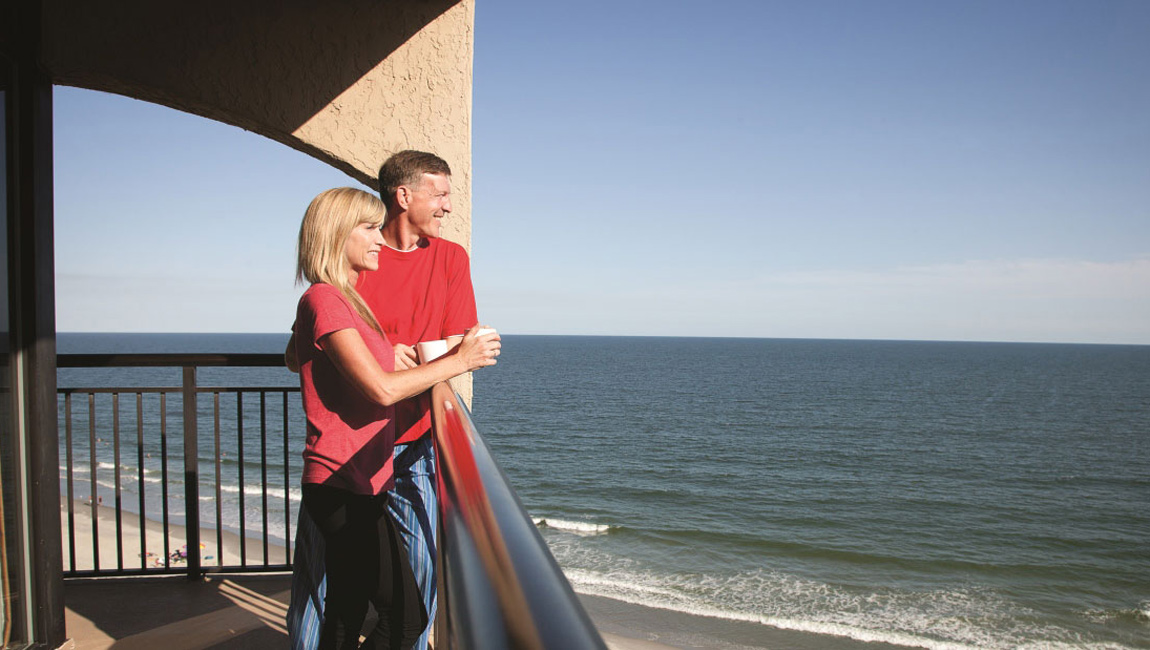 a couple on a balcony overlooking the sea