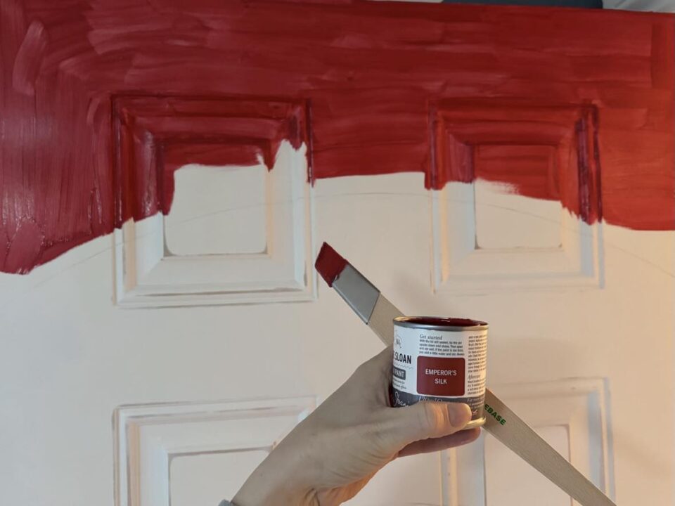 starting to paint the rainbow. I am holding up the red paint and a slanted paint brush