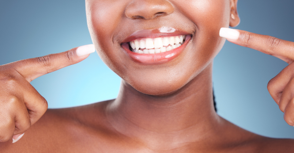 a black woman pointing to her very white teeth