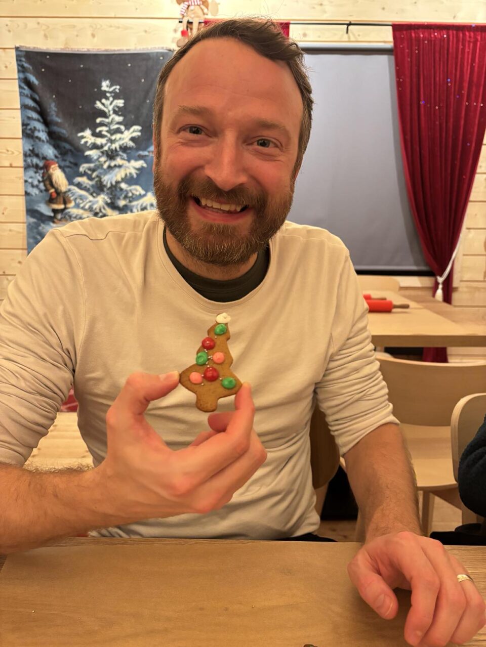 my husband proudly holding up his christmas tree shaped gingerbread