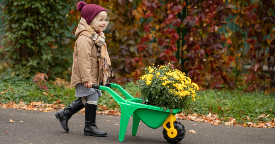 a small girl pushing a wheelbarrow helping with gardening