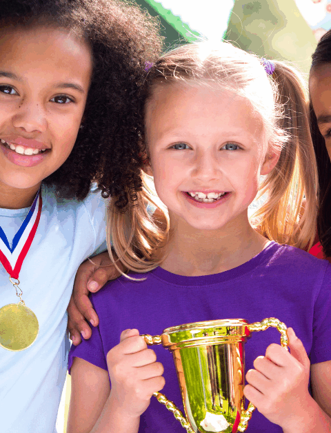 3 girls with medals and a trophy at a sports day