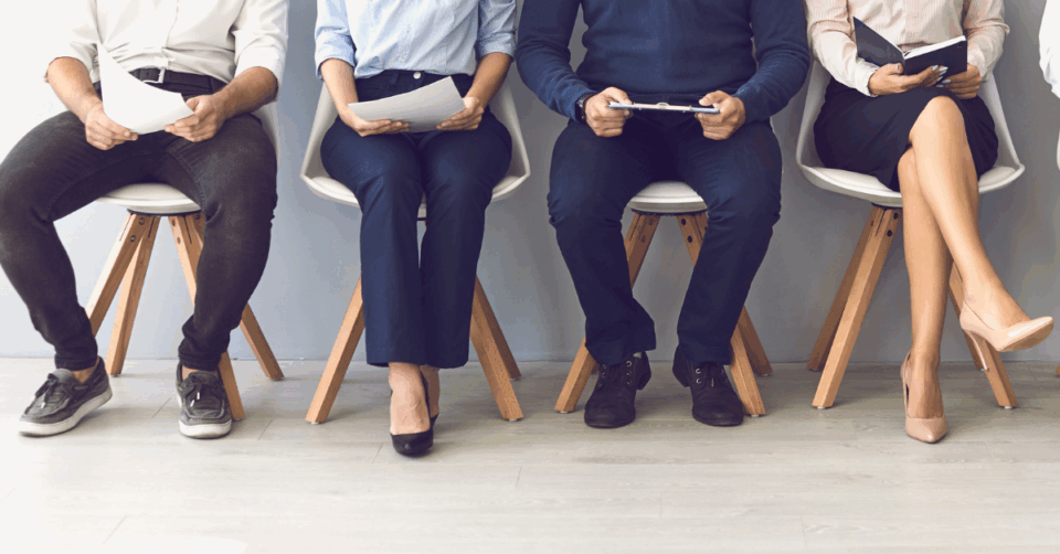 people sitting in chairs waiting for a job interview only legs on view