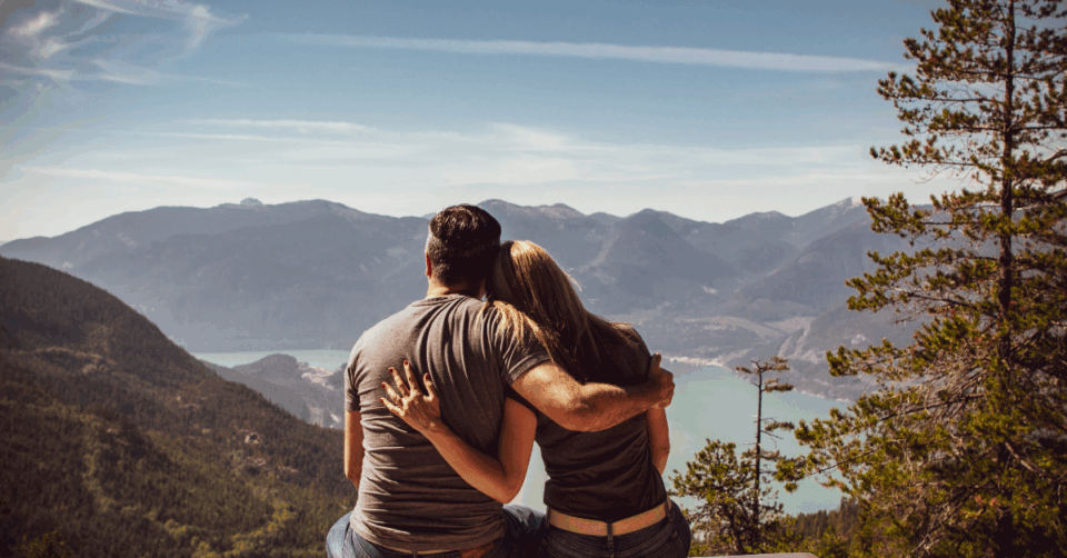 a couple looking out across hills and a lake
