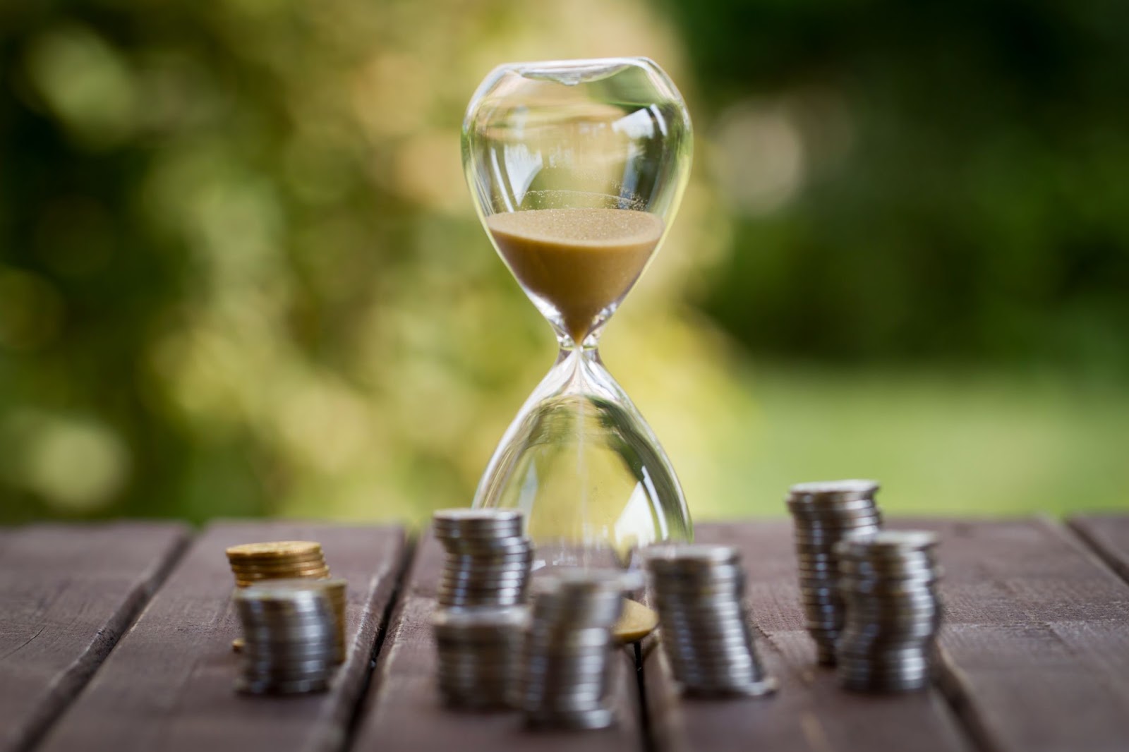a sand timer with money stacked around it