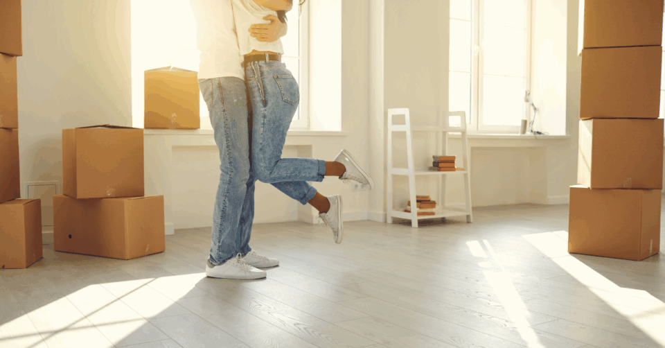 2 people in a new home with moving boxes around them