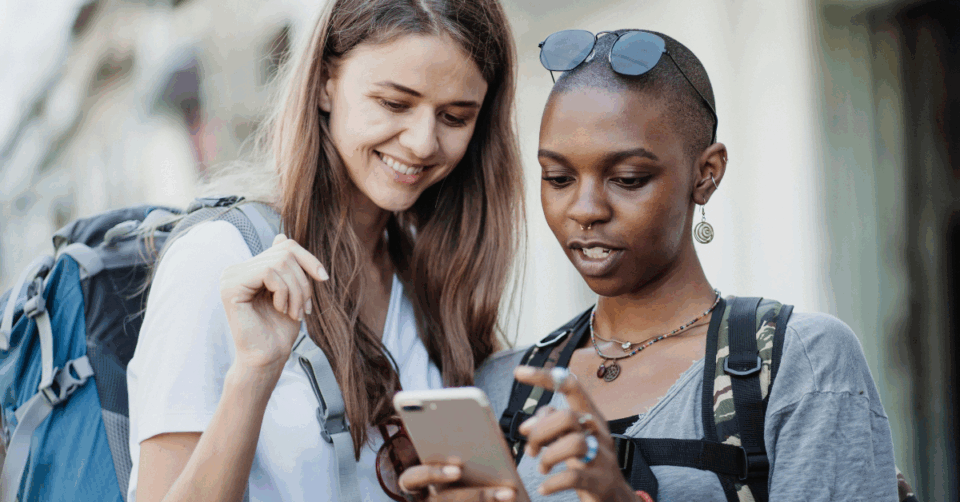 two girls looking at a phone whilst travelling