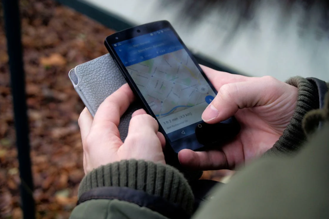 someone holding a mobile phone looking at a map 