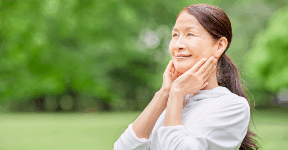 an older asian lady touching her face looking happy and healthy