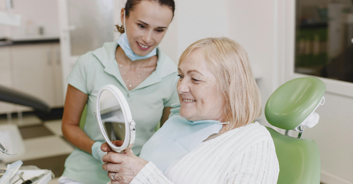 a dentist with a patient looking at her new dentures