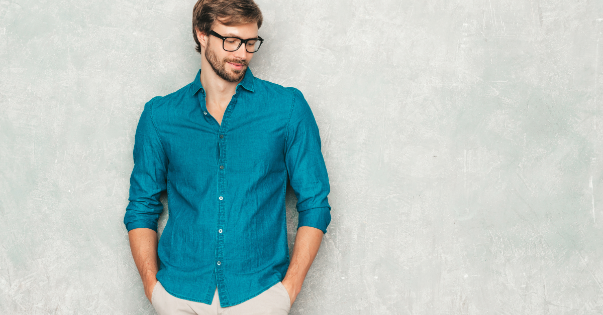 a man in a blue shirt leaning against a wall