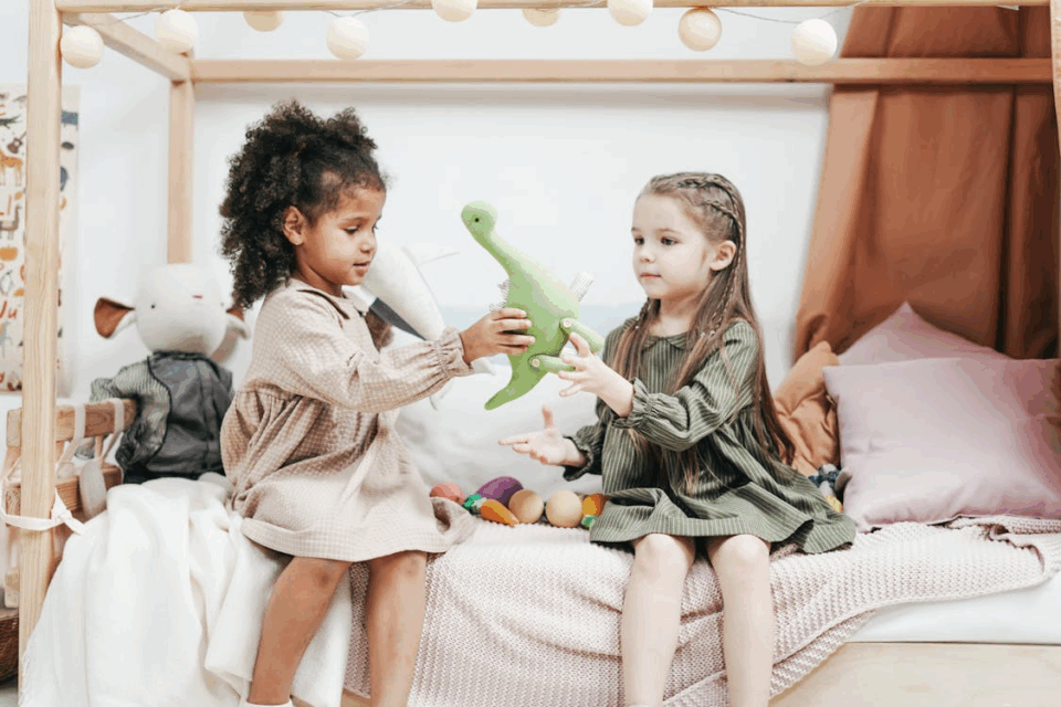 two little girls playing with a dinosaur toy