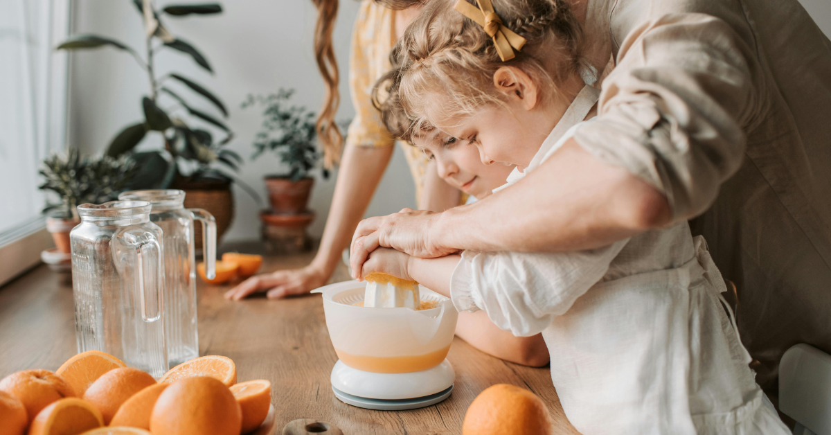 kids squeezing oranges with a parent