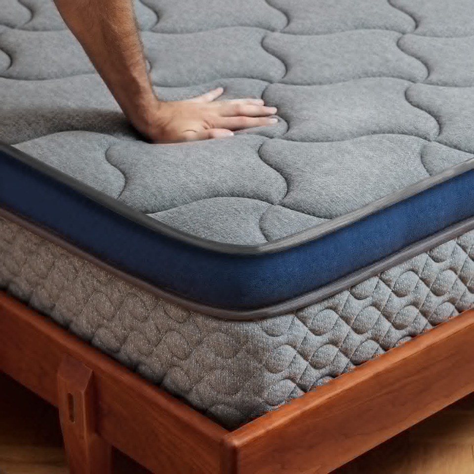 a hand pushing down on a mattress