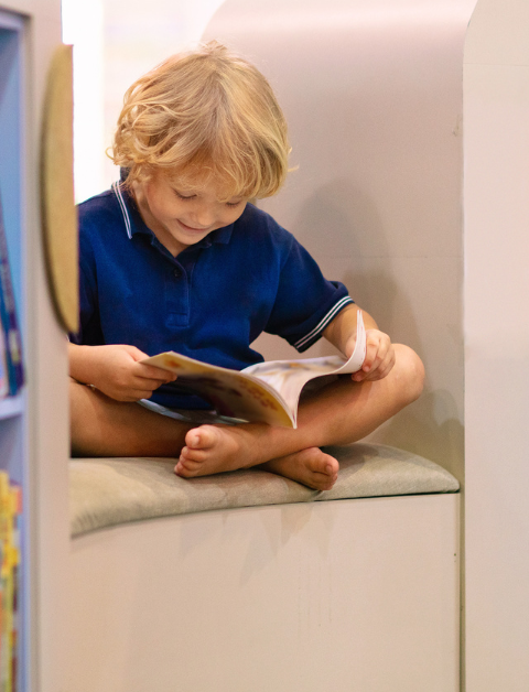 a child reading a book inbetween two book shelves