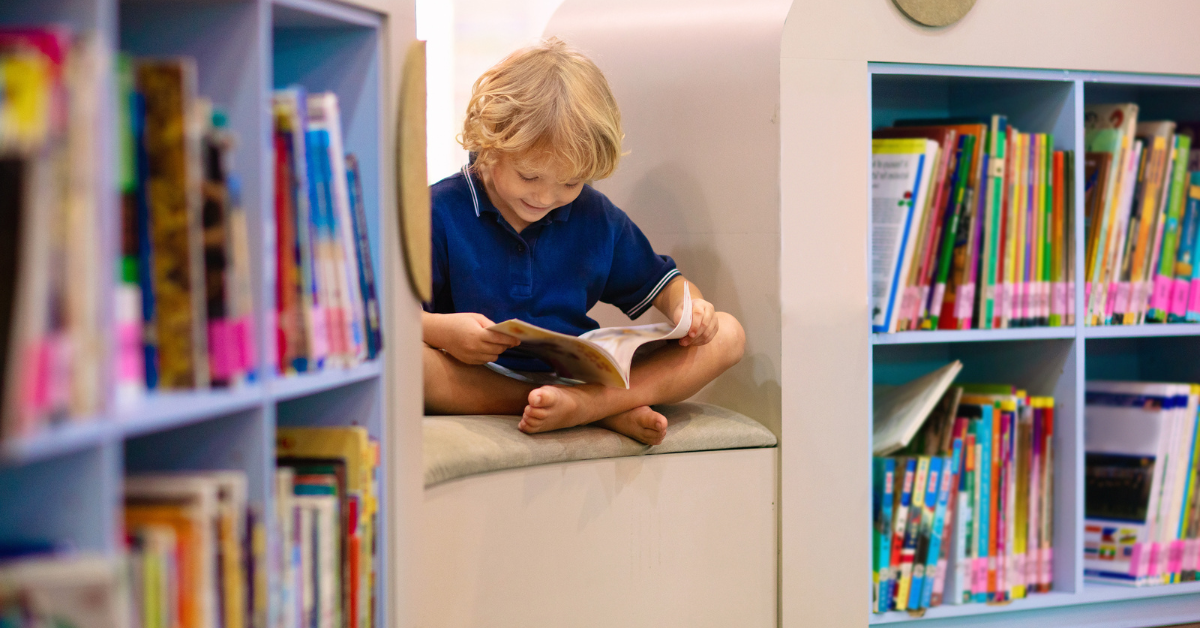 a child reading a book inbetween two book shelves