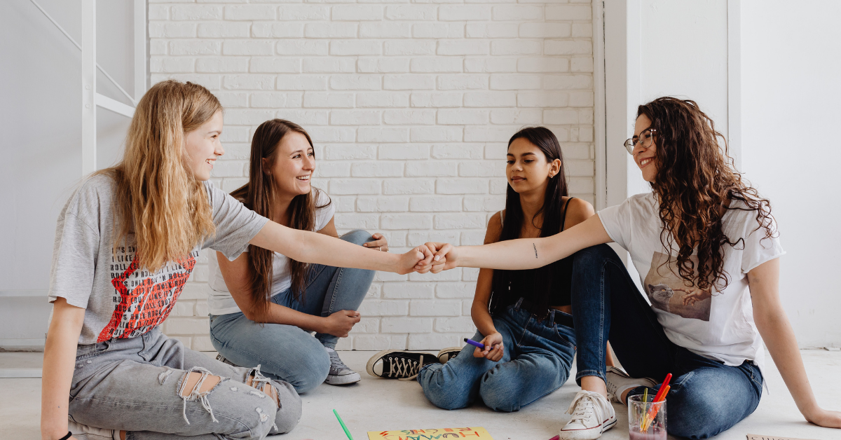 teen girls sat around looking like they are supporting one another