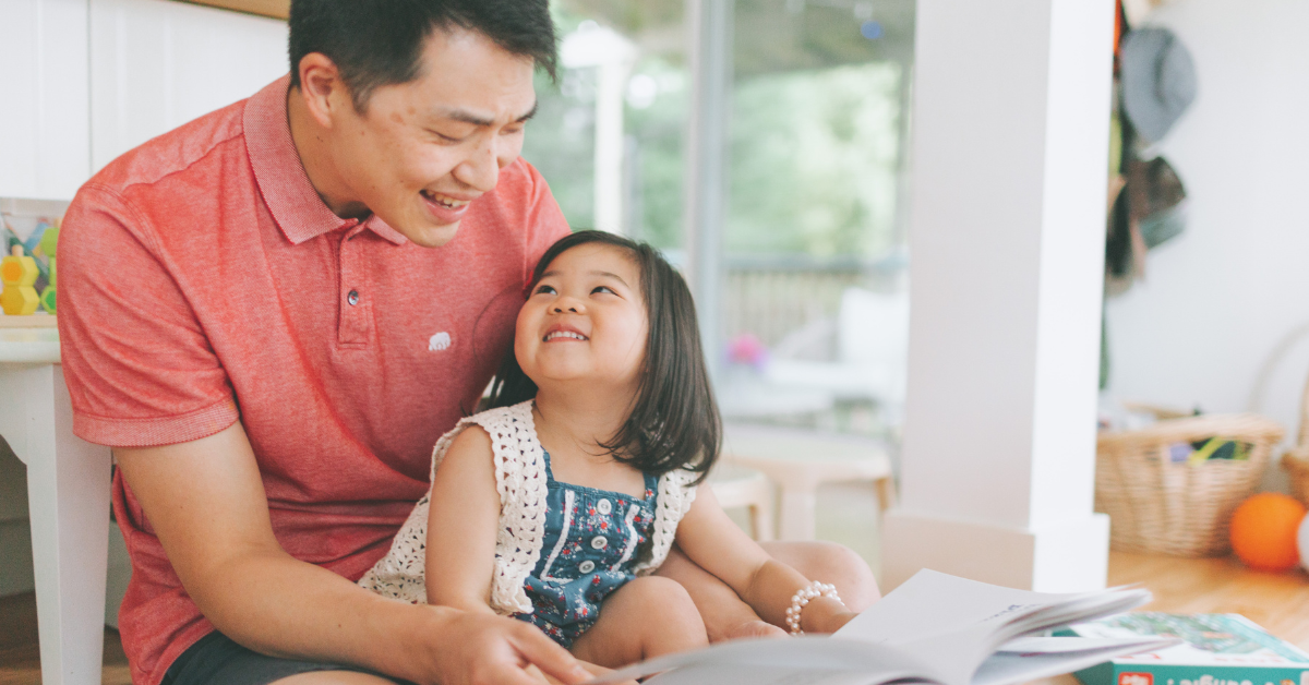 a dad with his daughter opening a gift and both smiling