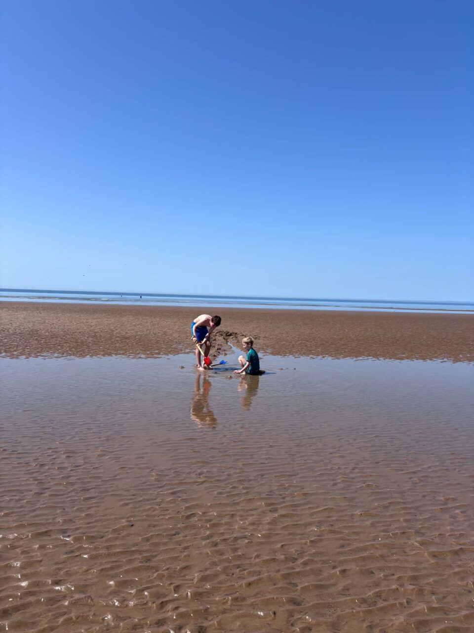 the boys playing in the paddling pools left behind by the sea