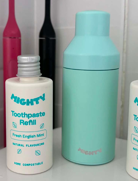 Mighty Mouthcare new V2 dispenser with 2 new home compostable refill tubes sat on a bathroom sink