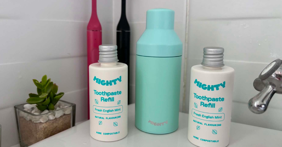 Mighty Mouthcare new V2 dispenser with 2 new home compostable refill tubes sat on a bathroom sink