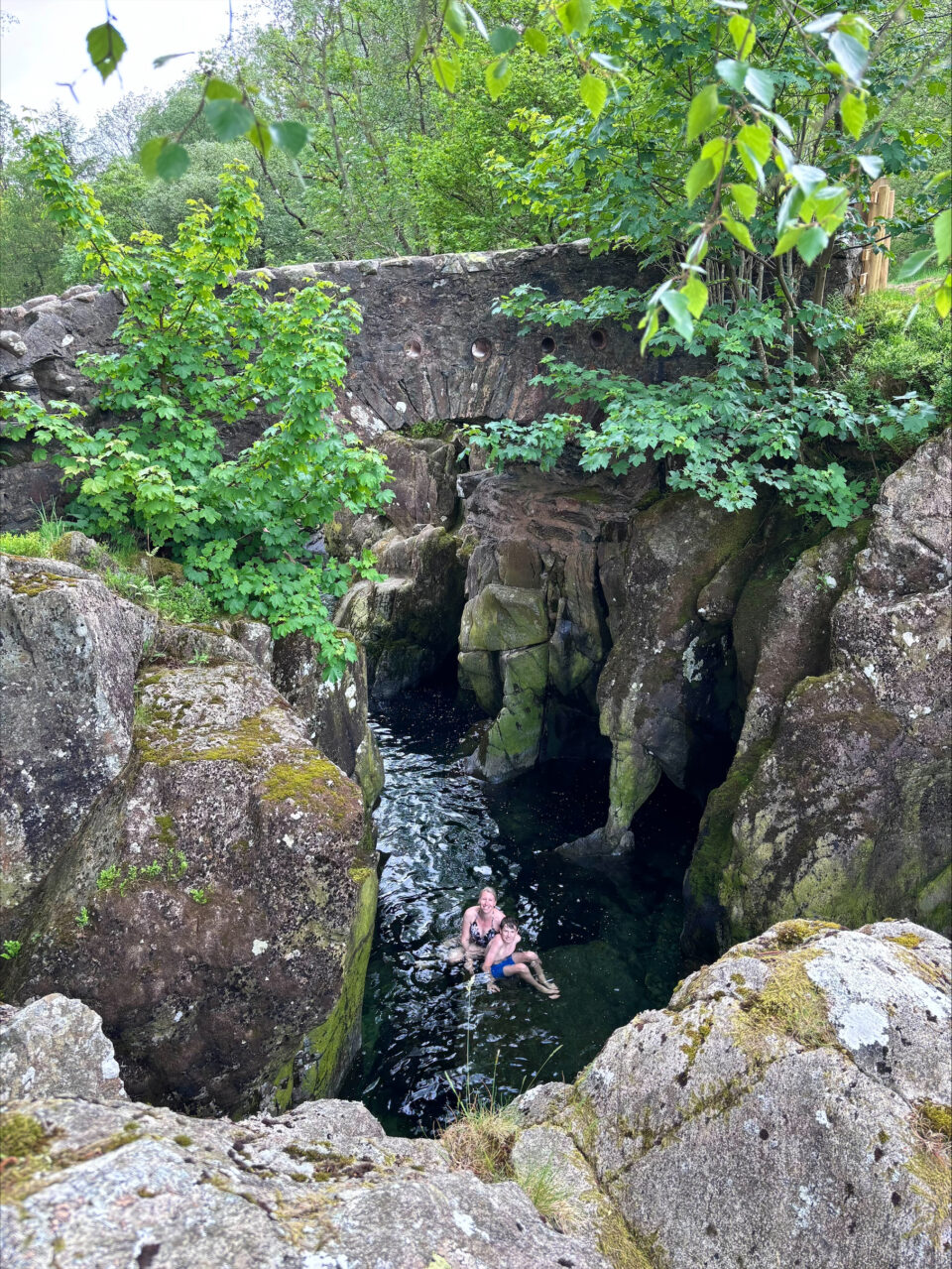 me and my son sat on a rock in the water under Birks Bridge