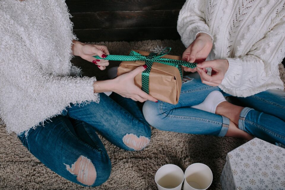 two people pulling a ribbon on a gift